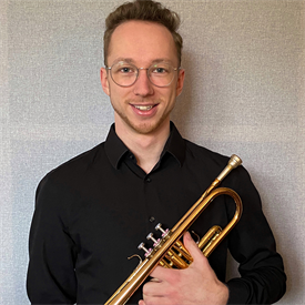 Dieses Bild zeigt Jan Vincenz. Er ist dunkelblond, trägt sein Haar kurz und trägt eine Brille. Er spielt Trompete in der HSD Big Band.